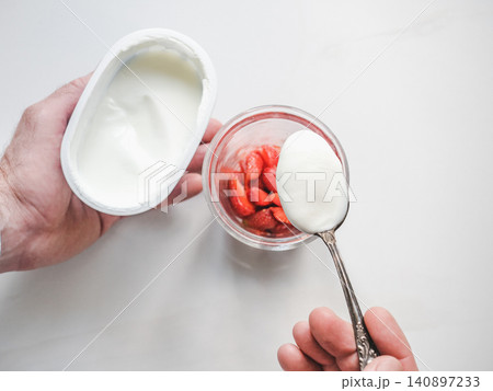 Hands stirring strawberry yogurt with a spoon Hands stirring strawberry yogurt with a spoon 140897233