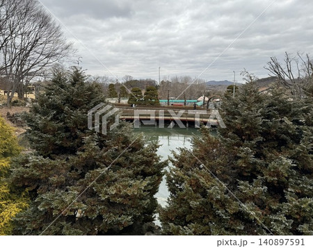 Winter view of Korean garden pond with bridge and shaped evergreens Winter view of Korean garden pond with bridge and shaped evergreens 140897591