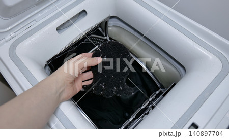 Hand holding a lint catcher full of lint over a washing machine 140897704