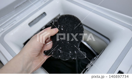 Hand holding a lint catcher full of debris from a washing machine 140897734