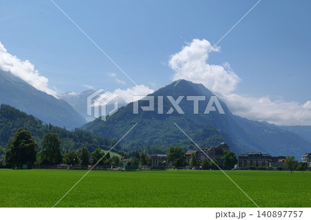 Scenic Mountain Landscape with Green Field and Alpine Village 140897757