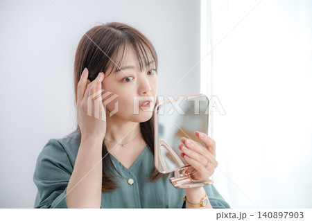 鏡を見て身だしなみを整える女性 鏡を見て身だしなみを整える女性 140897903