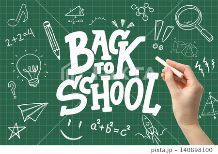 Hand writes back to school on chalkboard filled with drawings and educational symbols 140898100