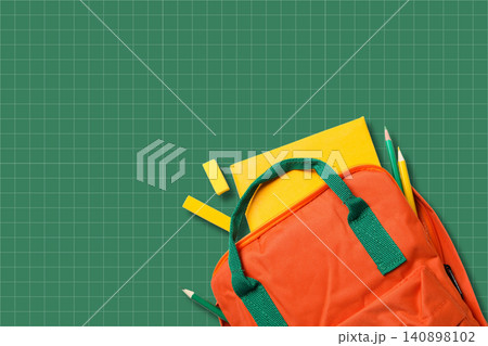 Back to school, Backpack filled with school supplies rests on green grid background 140898102