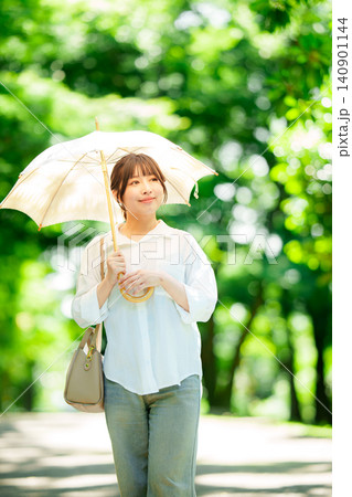 公園で日傘をさす女性 公園で日傘をさす女性 140901144