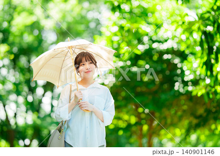 公園で日傘をさす女性 公園で日傘をさす女性 140901146
