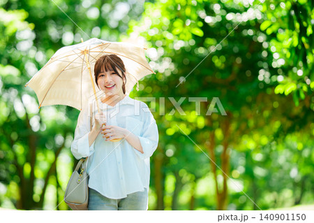 公園で日傘をさす女性 公園で日傘をさす女性 140901150