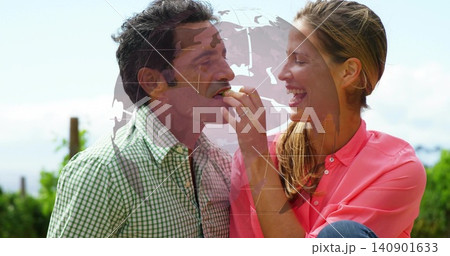 Feeding woman offering bite to man at park, wearing coral blouse and green shirt, left-hand ring Feeding woman offering bite to man at park, wearing coral blouse and green shirt, left-hand ring 140901633