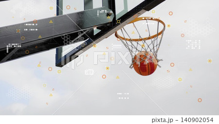 Descending orange basketball passing through net at outdoor court, with rim, overlay, copy space 140902054