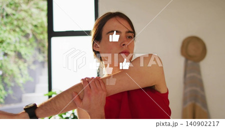 Stretching woman in red tank top pulling right arm across chest in studio, with thumbs-up overlays Stretching woman in red tank top pulling right arm across chest in studio, with thumbs-up overlays 140902217