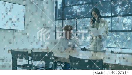 Talking office duo in blazer and shirt holding papers, phone while typing on laptop, binary overlay Talking office duo in blazer and shirt holding papers, phone while typing on laptop, binary overlay 140902515