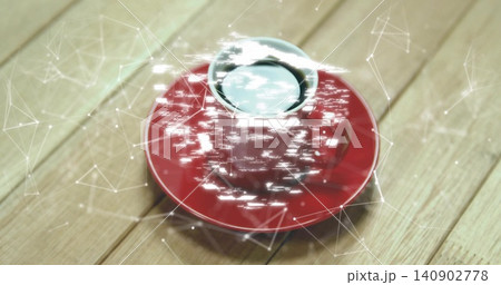 Showing red ceramic cup plus saucer holding dark liquid on light wood surface with digital overlay Showing red ceramic cup plus saucer holding dark liquid on light wood surface with digital overlay 140902778