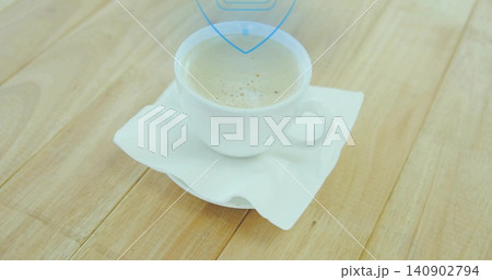 Sitting white ceramic cup holding light-brown coffee with thin crema on napkin at kitchen table 140902794