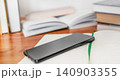 Black smartphone screen down on a table with books in background 140903355