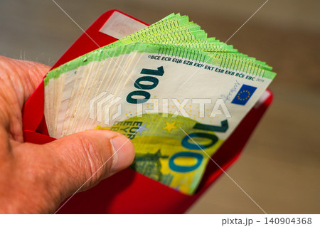 Hand Holding Red Envelope Filled with 100 Euro Banknotes, hidden Cash, Salary, Gift, Savings 140904368