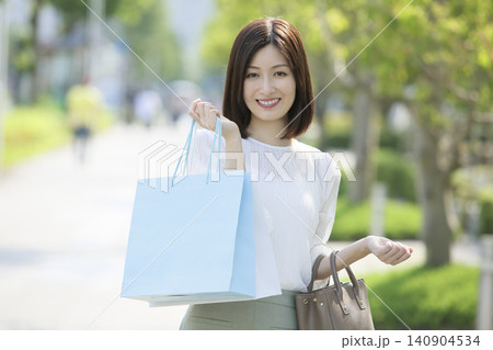 買い物袋を持って微笑む休日の女性 140904534