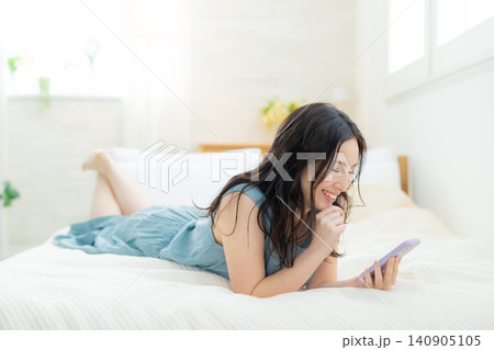 ベッドでスマホを見る女性 ベッドでスマホを見る女性 140905105