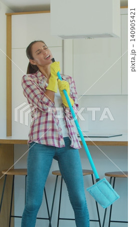 Vertical Video Young woman singing and dancing while cleaning her house. Vertical Video Young woman singing and dancing while cleaning her house. 140905421