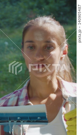 Vertical Video people, housework and housekeeping concept - woman in gloves cleaning window with rag and cleanser spray at home. 140905487