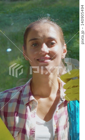 Vertical Video people, housework and housekeeping concept - woman in gloves cleaning window with rag and cleanser spray at home. Vertical Video people, housework and housekeeping concept - woman in gloves cleaning window with rag and cleanser spray at home. 140905494