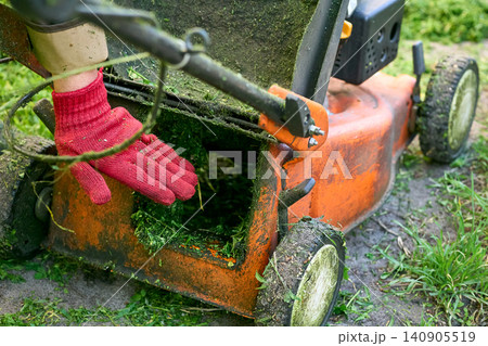 Worker checks the air flow of a lawn mower Worker checks the air flow of a lawn mower 140905519