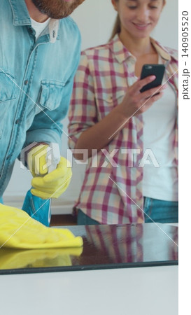 Vertical Video Man and woman as a professional cleaners in uniiform having fun during the work on the kitchen. Vertical Video Man and woman as a professional cleaners in uniiform having fun during the work on the kitchen. 140905520