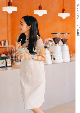 Young woman drinking iced coffee outside a chocolate shop Young woman drinking iced coffee outside a chocolate shop 140905620
