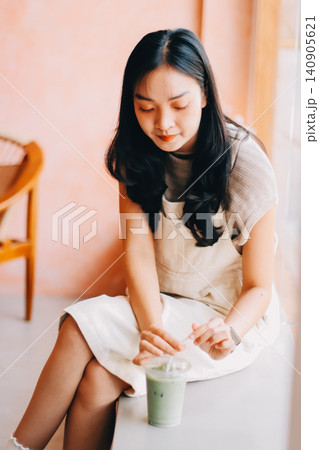 Young woman drinking iced coffee outside a chocolate shop Young woman drinking iced coffee outside a chocolate shop 140905621