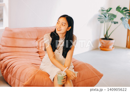Young woman drinking iced coffee outside a chocolate shop 140905622