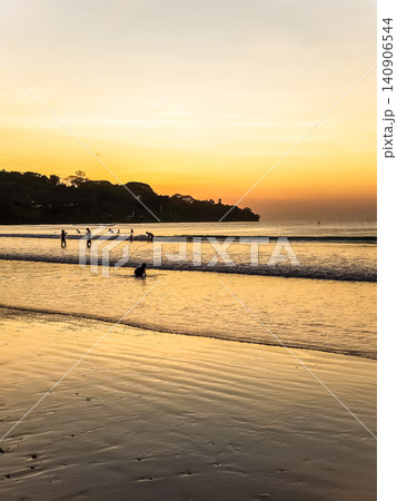 People Swimming in Ocean Waves at Tropical Beach During Vivid Orange Sunset with Tree Silhouette People Swimming in Ocean Waves at Tropical Beach During Vivid Orange Sunset with Tree Silhouette 140906544