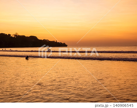 People Swimming in Ocean Waves at Tropical Beach During Vivid Orange Sunset with Tree Silhouette People Swimming in Ocean Waves at Tropical Beach During Vivid Orange Sunset with Tree Silhouette 140906545
