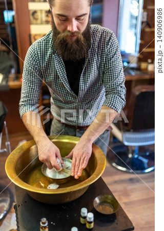 Barber preparing rich shaving foam in a traditional brass basin bowl Barber preparing rich shaving foam in a traditional brass basin bowl 140906986