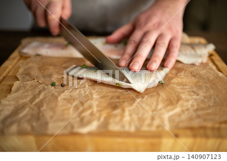 Slicing a seasoned raw fish fillet on a cutting board 140907123