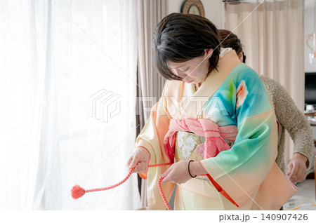室内で着物の帯を整える女性 室内で着物の帯を整える女性 140907426