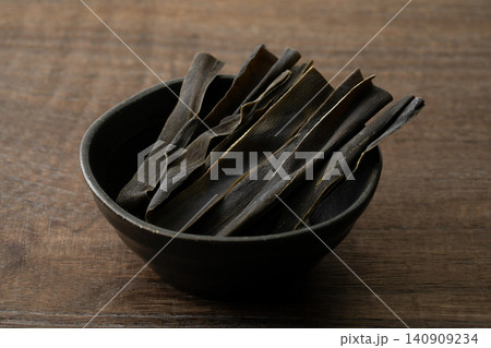 木目背景に小鉢に入れたおしゃぶり昆布 木目背景に小鉢に入れたおしゃぶり昆布 140909234