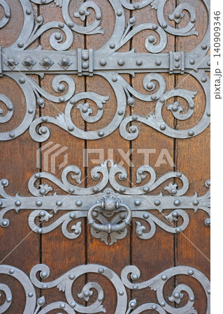 Decorative Ironwork on Historic Wooden Door Showcasing Ornate Metal Patterns Decorative Ironwork on Historic Wooden Door Showcasing Ornate Metal Patterns 140909346