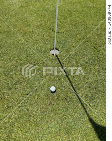 Golf Ball Near Hole on Green in Sunny Weather During the Game Golf Ball Near Hole on Green in Sunny Weather During the Game 140909744