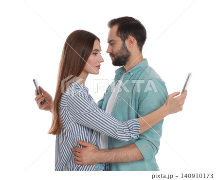 Couple addicted to smartphones hugging on white background. Relationship problems Couple addicted to smartphones hugging on white background. Relationship problems 140910173