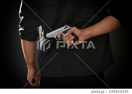 Professional killer with gun on black background, closeup 140910295