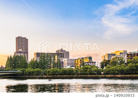 夕照に映える都市公園と川辺のビル 夕照に映える都市公園と川辺のビル 140910933