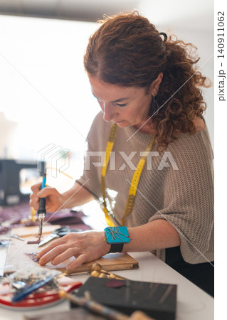 Craftswoman using soldering iron for handmade leather goods Craftswoman using soldering iron for handmade leather goods 140911062