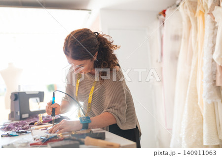 Craftswoman working on intricate details for custom clothing 140911063