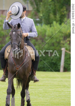 Rider on horse greets people while holding a hat in a green field during a sunny day Rider on horse greets people while holding a hat in a green field during a sunny day 140911092