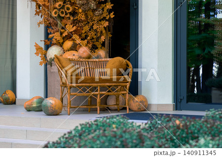 A cozy outdoor seating area decorated for fall with pumpkins, sunflowers, and warm-toned leaves creating a welcoming atmosphere A cozy outdoor seating area decorated for fall with pumpkins, sunflowers, and warm-toned leaves creating a welcoming atmosphere 140911345