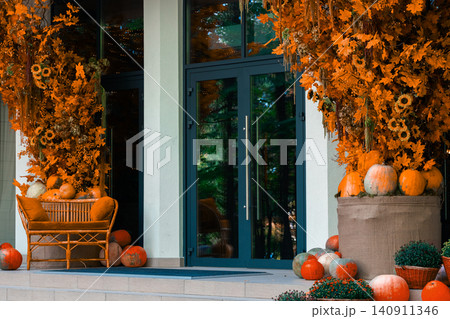 Festive orange autumn harvest decorations adorn a modern home entrance door 140911346