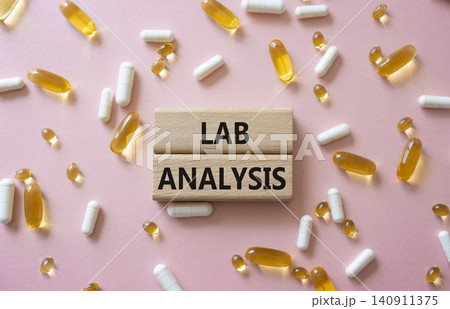 LAB ANALYSIS symbol. Concept word LAB ANALYSIS on wooden blocks. Beautiful pink background with pills. Medicine and LAB ANALYSIS. Copy space LAB ANALYSIS symbol. Concept word LAB ANALYSIS on wooden blocks. Beautiful pink background with pills. Medicine and LAB ANALYSIS. Copy space 140911375