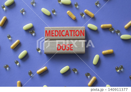 Medication dose symbol. Concept word Medication dose on wooden blocks. Beautiful purple background with pills. Medicine and Medication dose. Copy space 140911377