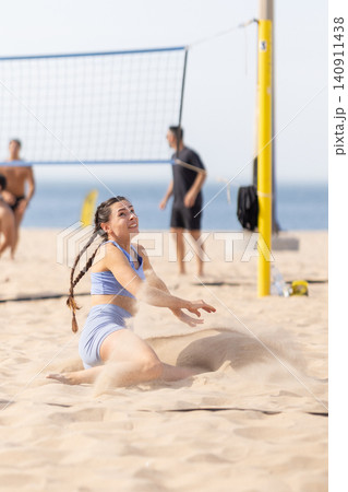 Group of people play volleyball on the beach during a sunny day with one player diving for the ball on the sand Group of people play volleyball on the beach during a sunny day with one player diving for the ball on the sand 140911438