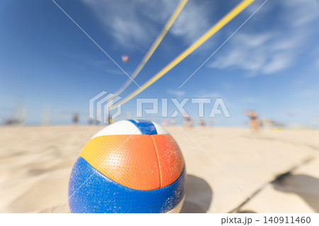 Beach volleyball game taking place on sunny day with court and ball in focus Beach volleyball game taking place on sunny day with court and ball in focus 140911460