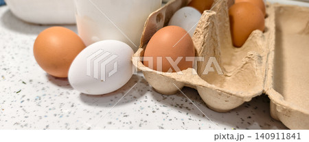 Fresh farm eggs, brown and white, in an open eco-friendly cardboard carton and resting on a kitchen counter, symbolizing healthy eating and natural produce. Fresh farm eggs, brown and white, in an open eco-friendly cardboard carton and resting on a kitchen counter, symbolizing healthy eating and natural produce. 140911841
